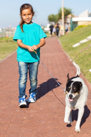 pretty little girl walking a dog outdoorsの写真素材