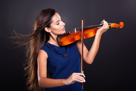 beautiful young woman playing violin on black backgroundの写真素材