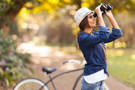 attractive young woman using binoculars bird watching at the parkの写真素材