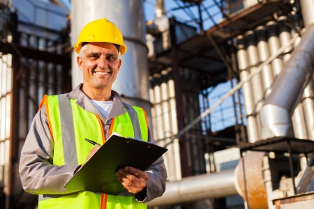 happy middle aged oil industry worker in refinery plant happy middle aged oil industry worker in refinery plant