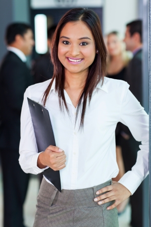 beautiful young indian office worker holding a clipboard in officeの写真素材