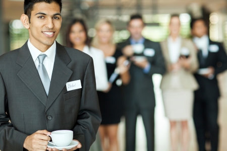 smiling young indian businessman having coffee break during seminar の写真素材