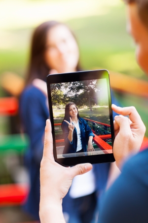 teen boy taking photos of his girlfriend using a tablet computerの写真素材