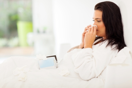 sick woman in bed blowing her nose