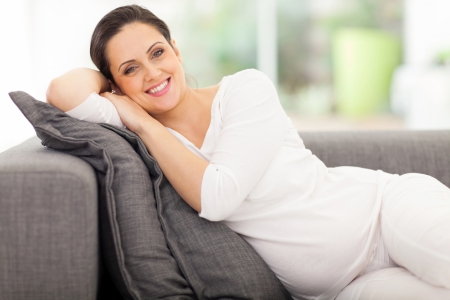 pregnant woman lying on a couch looking happyの写真素材