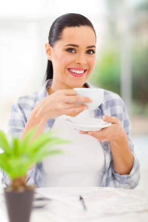 happy young adult woman drinking coffee at home while calculating home financesの写真素材
