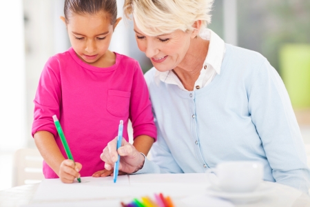 loving grandma teaching granddaughter drawing at homeの写真素材