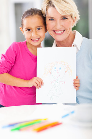 cute little girl showing drawing picture of her grandmaの写真素材