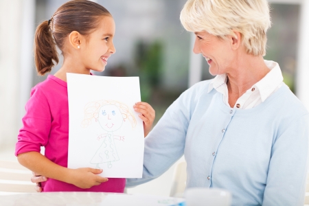 loving little granddaughter showing drawing of her grannyの写真素材