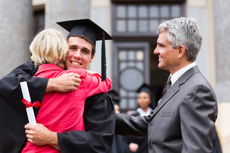 happy male graduate hugging his mother at graduation ceremonyの写真素材
