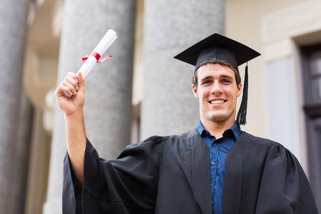 happy male university student holding his graduation certificateの写真素材