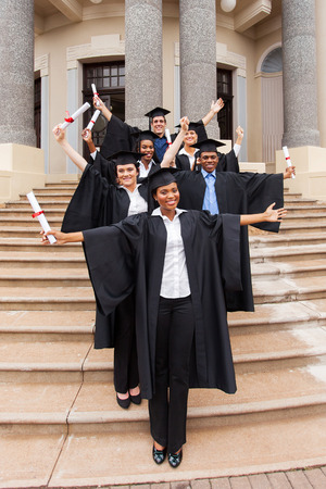 excited graduates standing outside college buildingの写真素材