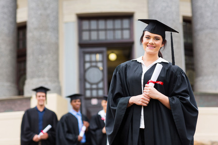 portrait of pretty female graduate wearing graduation gown at college graduationの写真素材