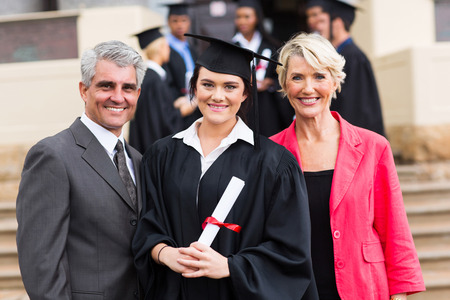 pretty young graduate with happy parents at graduation ceremonyの写真素材