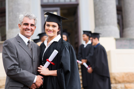 pretty female graduate with her father at university graduationの写真素材