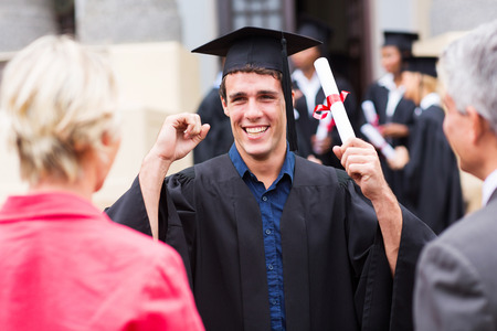 excited male graduate holding his diploma at graduationの写真素材