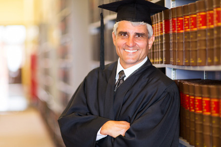 portrait of senior graduate with arms crossed in libraryの写真素材