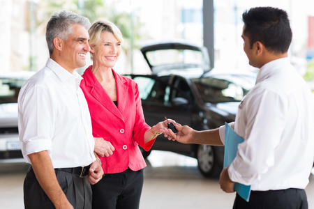 senior couple receiving car key after buying a new carの写真素材