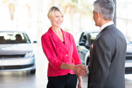 beautiful middle aged woman handshaking with car dealerの写真素材