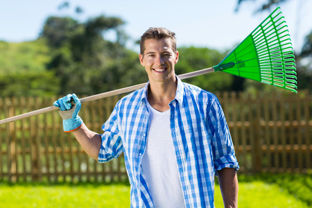 handsome man holding rake in the gardenの写真素材