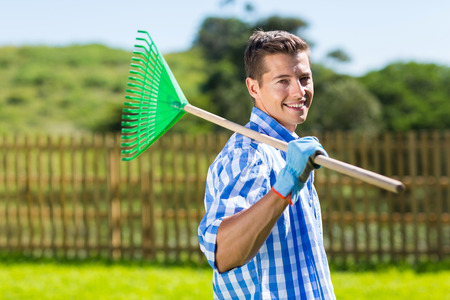 young man with fan rake in his home gardenの写真素材