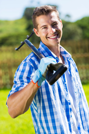 good looking young man holding a garden forkの写真素材