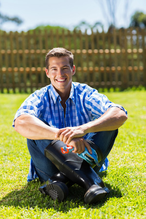 handsome young man sitting on the lawn relaxing after garden workの写真素材