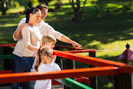 young family looking at a pond in the parkの写真素材