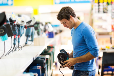 handsome young man shopping for sander in hardware storeの写真素材