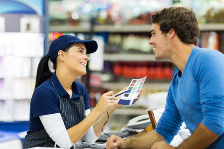 female paint store worker talking to customer over the counterの写真素材