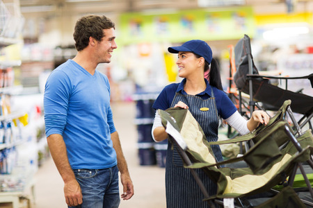 friendly saleswoman selling camping chair to customer in supermarketの写真素材