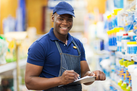 happy african shop assistant checking stock in supermarketの写真素材