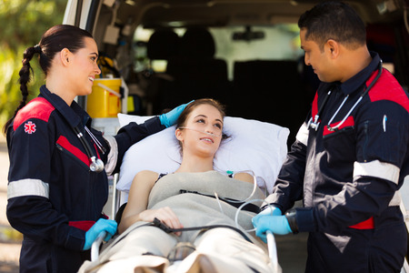 friendly paramedic comforting young patient before transporting her to hospital