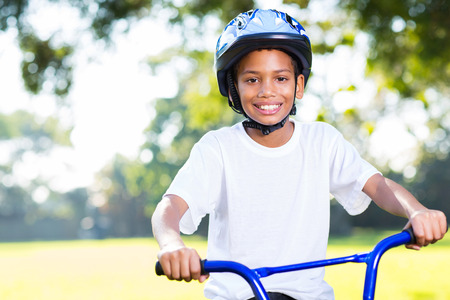 happy young indian boy riding a bike outdoorsの写真素材