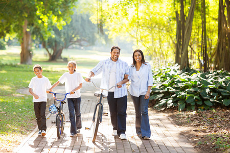 happy indian family of four walking outdoors in the parkの写真素材