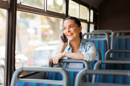 beautiful female commuter talking on cell phone while taking bus to work beautiful female commuter talking on cell phone while taking bus to work