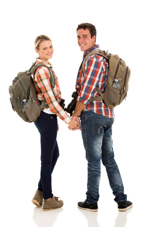 happy young couple with backpacks looking back on white backgroundの写真素材