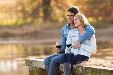 young couple relaxing outdoors having red wineの写真素材