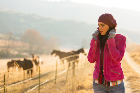 beautiful young woman at horse farm in the cold winter morning 