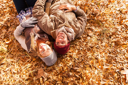 overhead view of happy young couple lying on autumn leavesの写真素材