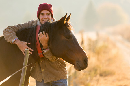 portrait of happy man hugging his horse in the ranchの写真素材