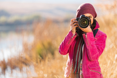 young woman photographing outdoors in autumnの写真素材