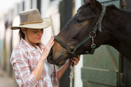 caring cowgirl talking to a horse in farm houseの写真素材