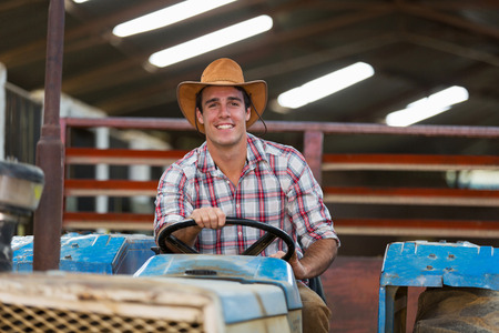 happy young farmer driving tractor
