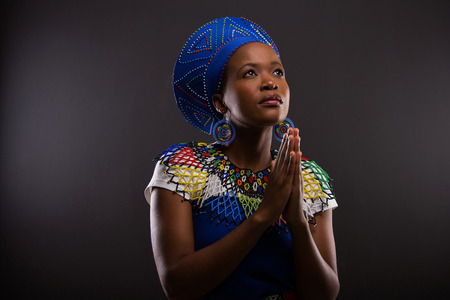 religious young african woman praying over black background