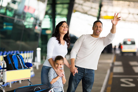 handsome man and his family hailing taxi at airportの写真素材