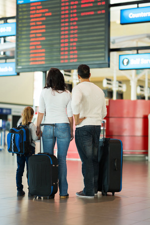 rear view of family checking flight information at airportの写真素材