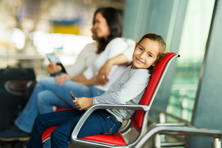 lovely little girl holding a tablet pc at airport with parents in backgroundの写真素材