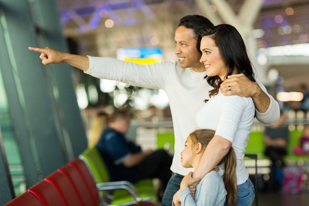 happy family standing at airport and pointing outside の写真素材