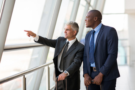 good looking business travelers pointing at airportの写真素材